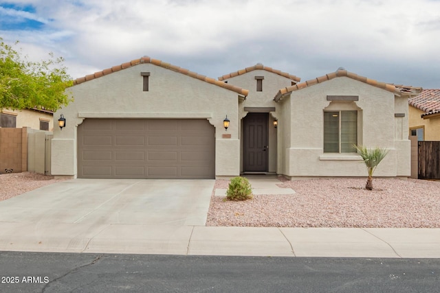 mediterranean / spanish home with stucco siding, fence, concrete driveway, a garage, and a tiled roof