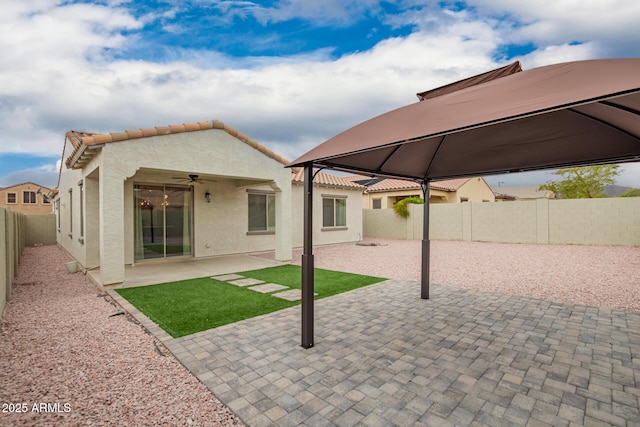 rear view of property with a patio area, stucco siding, a tiled roof, and a fenced backyard