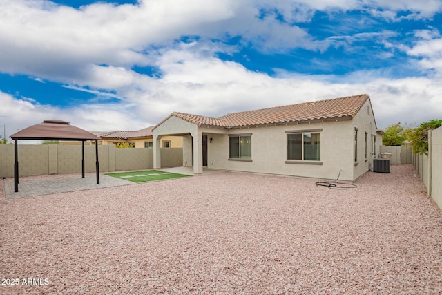 back of house with a fenced backyard, stucco siding, a gazebo, a tiled roof, and a patio area