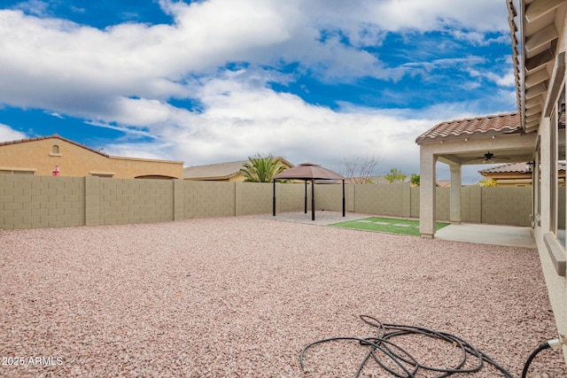 view of yard featuring a ceiling fan, a gazebo, a fenced backyard, and a patio