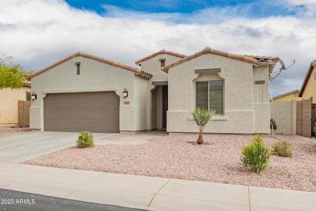 mediterranean / spanish house with stucco siding, an attached garage, concrete driveway, and fence