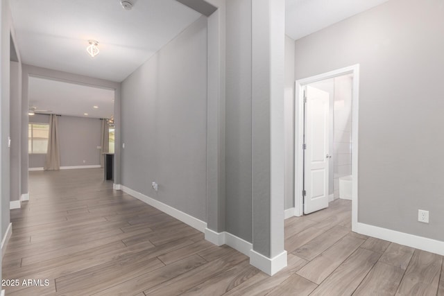 hallway featuring baseboards and light wood finished floors