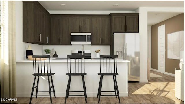 25140 N 174th Ave, Surprise, AZ 85387 - kitchen with white microwave, refrigerator with ice dispenser, dark brown cabinets, a peninsula, and light wood-style floors