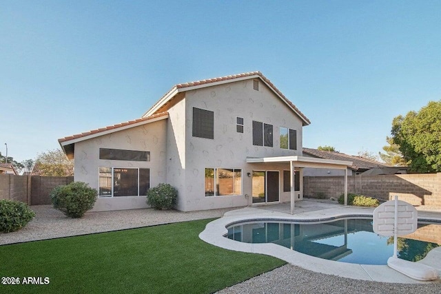 rear view of property featuring a fenced in pool and a patio