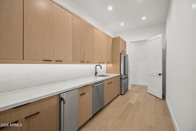 kitchen with light brown cabinetry, modern cabinets, appliances with stainless steel finishes, and a sink