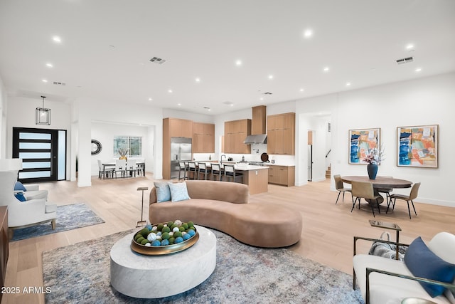 living room featuring visible vents, light wood finished floors, and recessed lighting