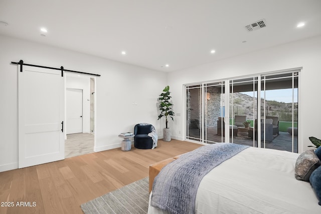 bedroom with visible vents, a barn door, access to exterior, light wood-type flooring, and recessed lighting