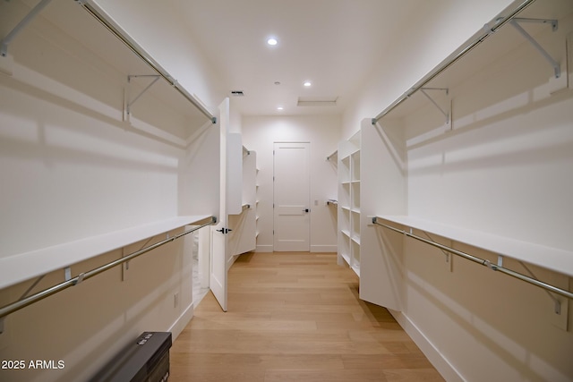 walk in closet with light wood finished floors