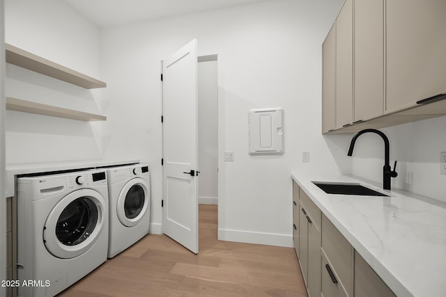 laundry area with washing machine and dryer, a sink, light wood-style floors, baseboards, and cabinet space