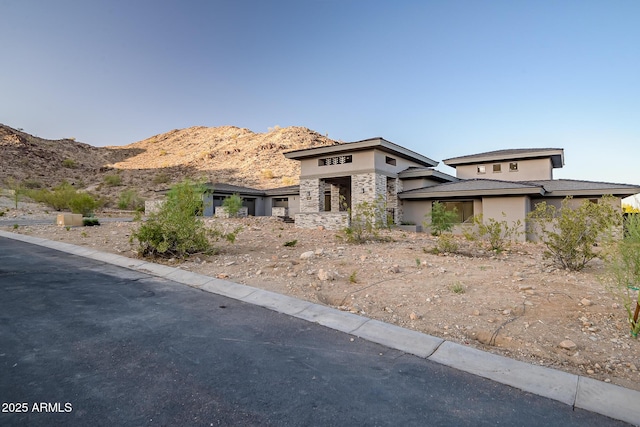 prairie-style home with a mountain view, stucco siding, and stone siding