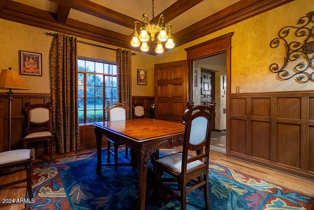 dining room with ornamental molding, a chandelier, beamed ceiling, and light wood-type flooring