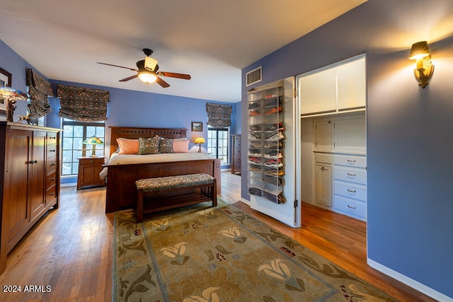 bedroom with a closet, ceiling fan, wood-type flooring, and a walk in closet