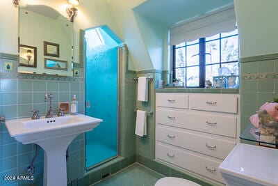 bathroom with toilet, lofted ceiling, a shower with shower door, and tile walls