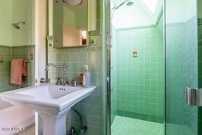 bathroom featuring an enclosed shower, sink, and tile walls