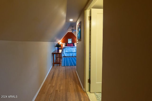 corridor with lofted ceiling and light hardwood / wood-style floors