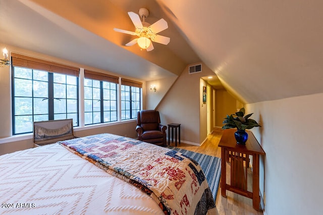 bedroom with ceiling fan, vaulted ceiling, and light hardwood / wood-style floors