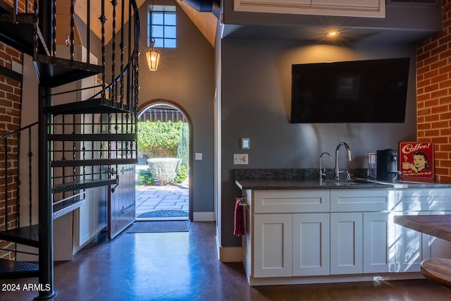 kitchen featuring white cabinetry, sink, a high ceiling, and dark stone counters