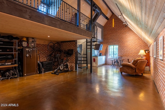 interior space featuring concrete floors, brick wall, and high vaulted ceiling