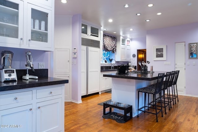 kitchen featuring a breakfast bar area, a center island, white cabinets, and light wood-type flooring