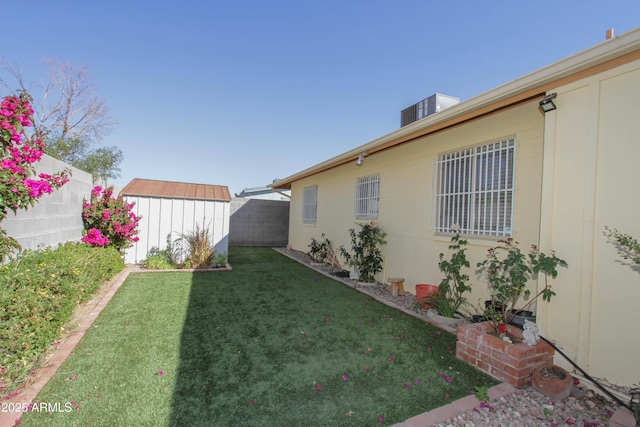 view of yard featuring a storage shed, a fenced backyard, and an outdoor structure