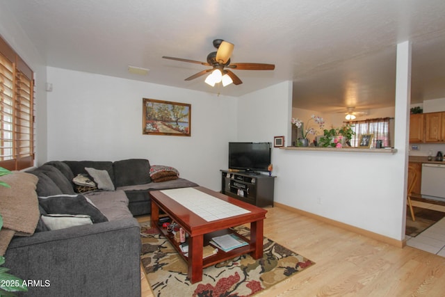 living room featuring light wood-type flooring, baseboards, and a ceiling fan