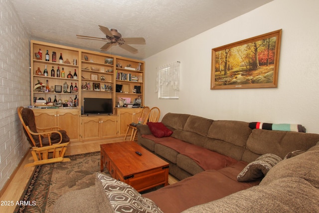 living room featuring a textured ceiling, ceiling fan, and wood finished floors