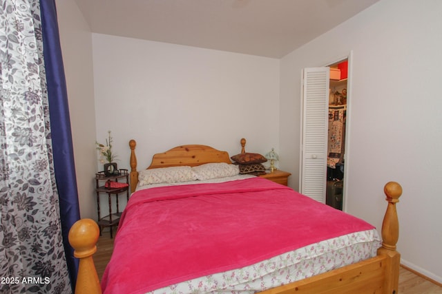 bedroom with a closet, wood finished floors, and baseboards