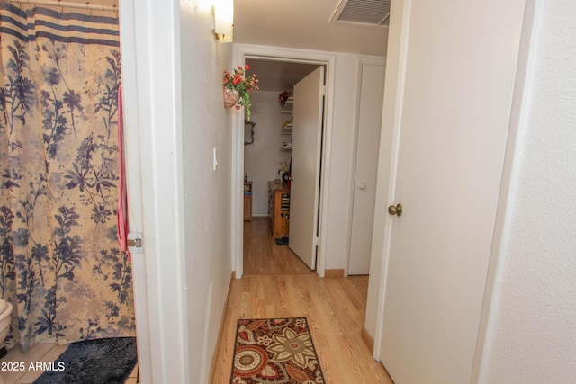 hall with light wood-style floors and visible vents