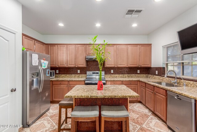 kitchen featuring stainless steel appliances, light stone countertops, sink, and backsplash