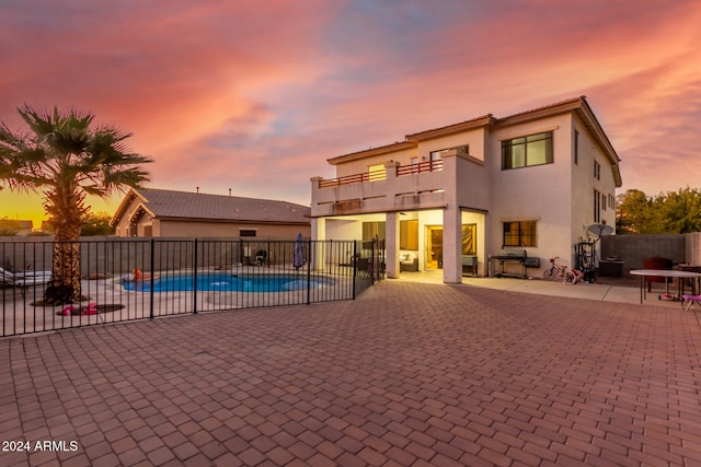 pool at dusk featuring a patio area