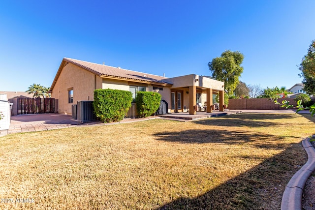 rear view of property with a lawn, a patio area, and central AC