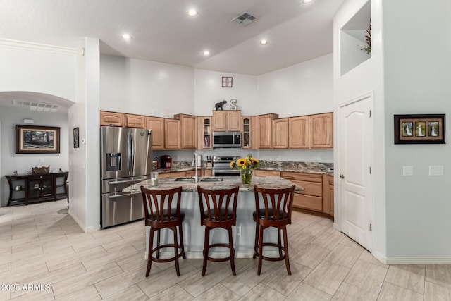 kitchen featuring a kitchen island with sink, a high ceiling, sink, a kitchen bar, and stainless steel appliances