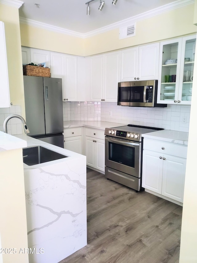 kitchen featuring light stone countertops, appliances with stainless steel finishes, white cabinetry, sink, and backsplash