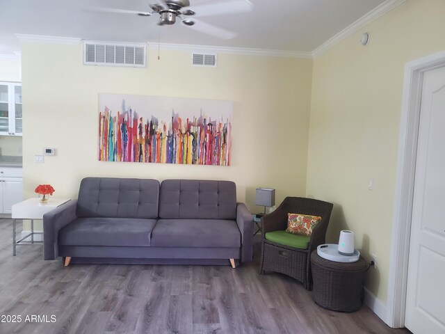 living room with light wood-type flooring, ceiling fan, and ornamental molding