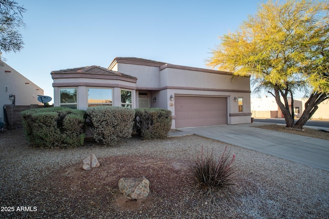 view of front facade with driveway, a tiled roof, stucco siding, and an attached garage
