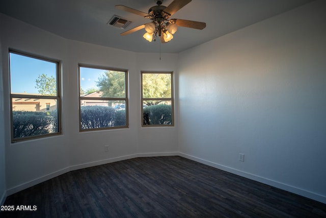 spare room featuring dark wood-style floors, visible vents, ceiling fan, and baseboards