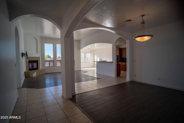 unfurnished living room featuring light tile patterned floors, a fireplace, visible vents, and baseboards