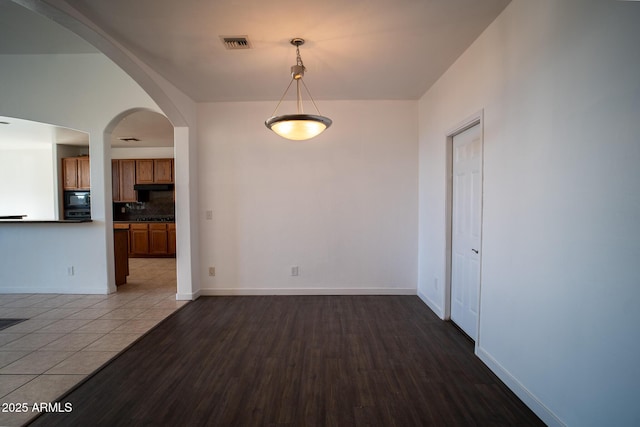 unfurnished dining area featuring baseboards, visible vents, and wood finished floors