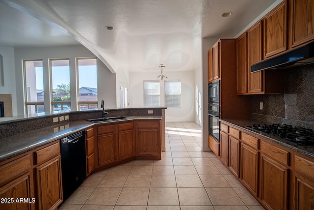 kitchen featuring a chandelier, brown cabinetry, black appliances, dark countertops, and a sink