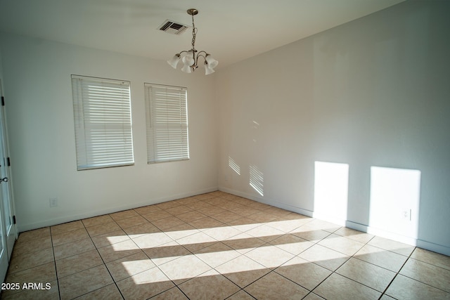 spare room with light tile patterned flooring, visible vents, a chandelier, and baseboards