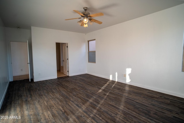 spare room with dark wood-style flooring, a ceiling fan, and baseboards