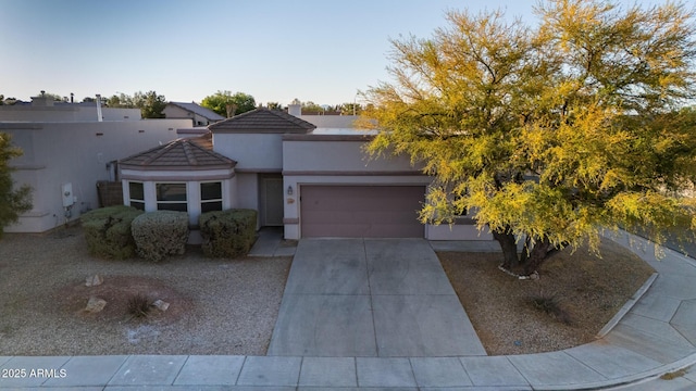 view of front of home with a garage, a tiled roof, a chimney, concrete driveway, and stucco siding