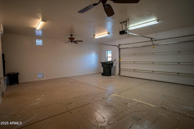 garage with a garage door opener, ceiling fan, visible vents, and baseboards