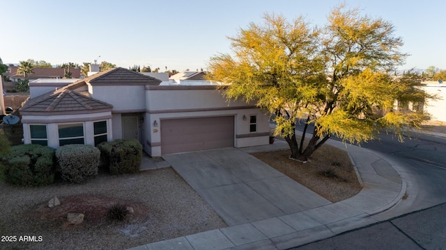view of front of property with driveway, a chimney, a tiled roof, stucco siding, and a garage