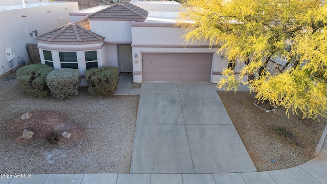 view of front of home with a tile roof, driveway, a garage, and stucco siding