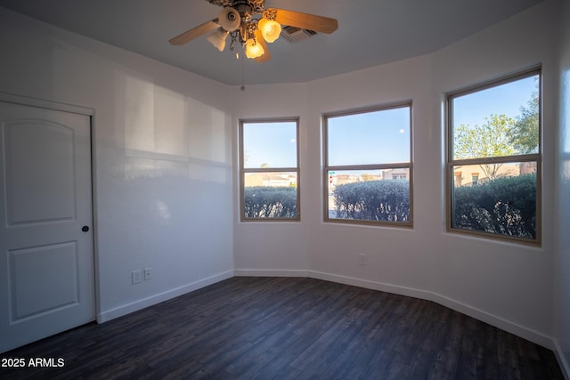 empty room with visible vents, ceiling fan, baseboards, and dark wood finished floors
