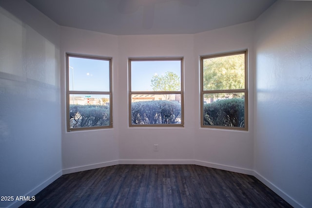 unfurnished room with dark wood finished floors and baseboards