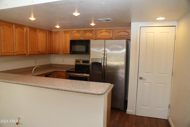 kitchen featuring light stone countertops, a textured ceiling, appliances with stainless steel finishes, dark hardwood / wood-style flooring, and kitchen peninsula