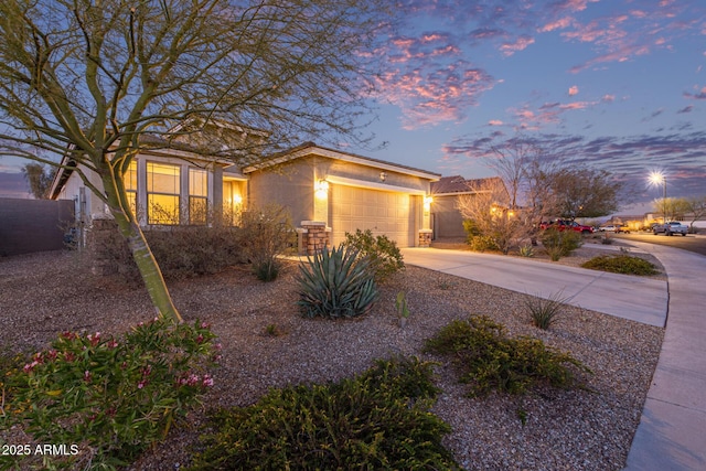 view of front of property featuring stucco siding, driveway, an attached garage, and fence