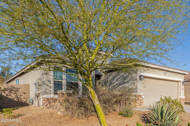 view of property exterior with driveway, a garage, stone siding, and stucco siding